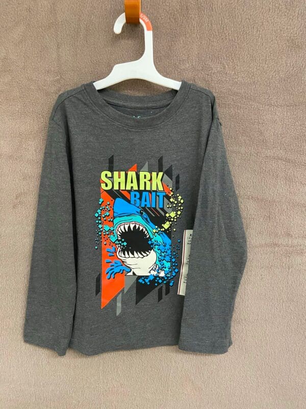 A gray long sleeve shirt with shark and shark fin designs.