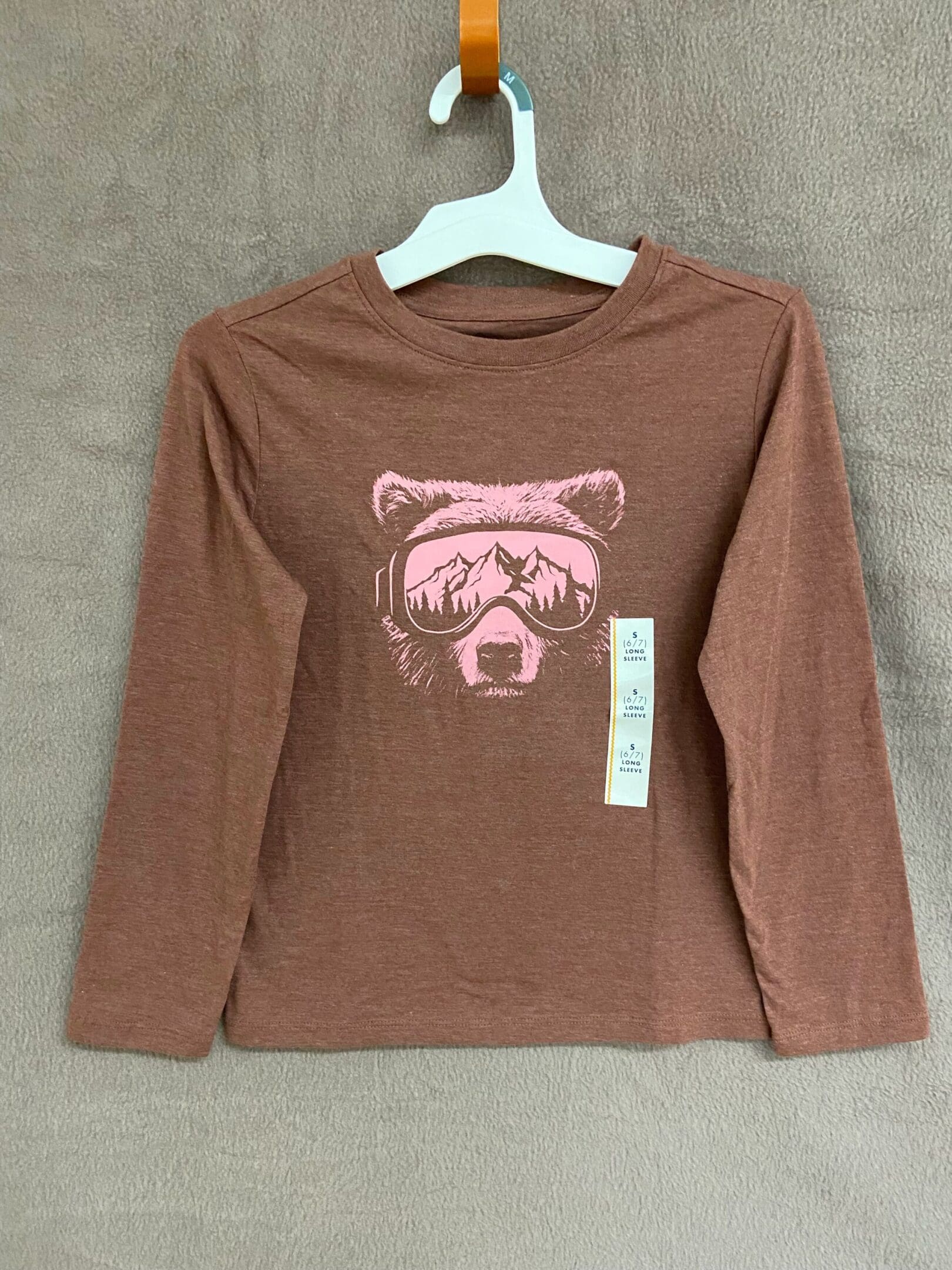 A brown long sleeve shirt with a pink bear on it.